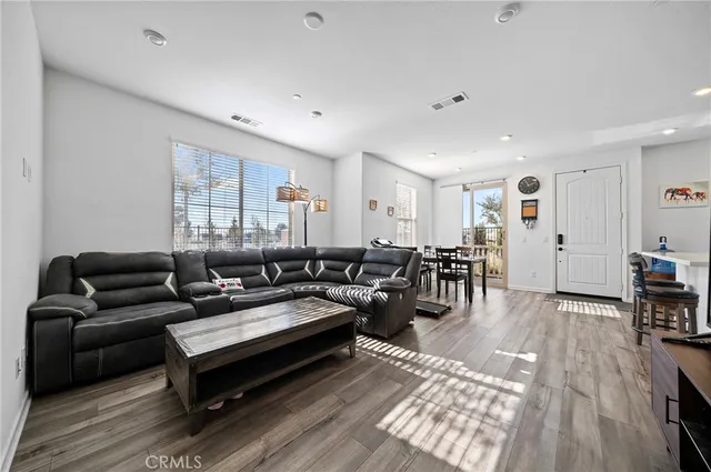 a living room with furniture a wooden floor and next to a window