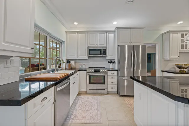 a kitchen with granite countertop white cabinets and stainless steel appliances