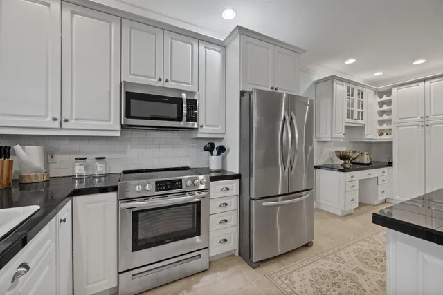 a kitchen with white cabinets and stainless steel appliances