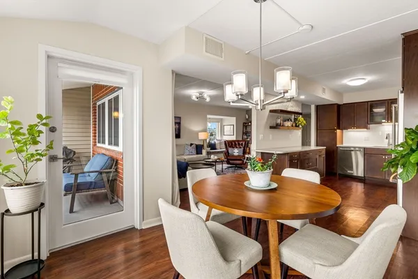 a dining room with wooden floor a chandelier a wooden table and chairs
