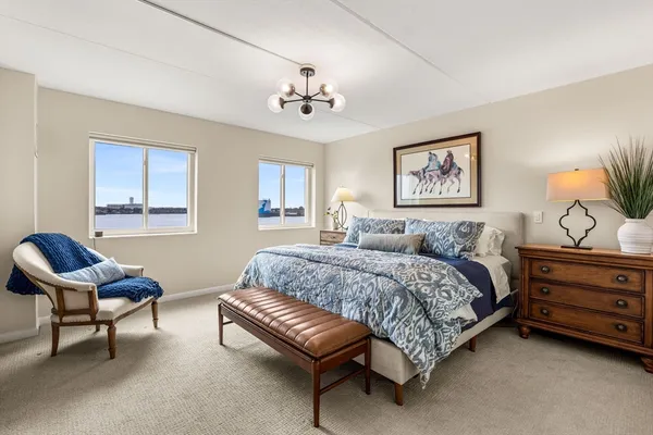 a spacious bedroom with a bed a couch and a chandelier