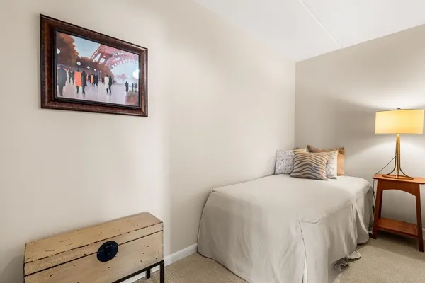 a bedroom with a bed and a lamp on dresser