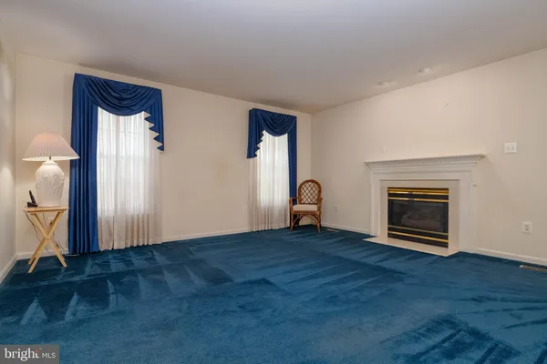 an empty room with wooden floor a fireplace and window