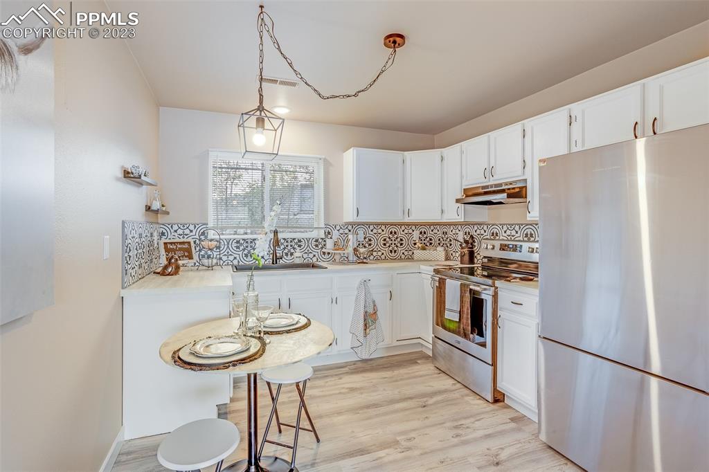 2139 Preuss Road, Unit C Colorado Springs, CO 80910 - Photo 4 of 14 a kitchen with stainless steel appliances a sink a stove a refrigerator cabinets a dining table and chairs