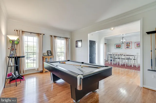 a living room with hard wood flooring and pool table