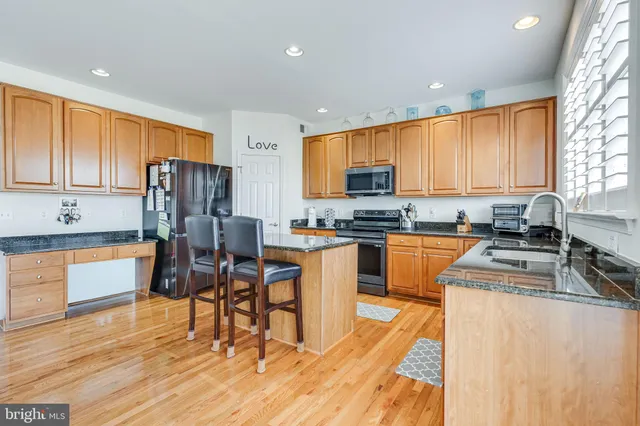 a kitchen with stainless steel appliances granite countertop a refrigerator a stove top oven a sink dishwasher and cabinets with wooden floor