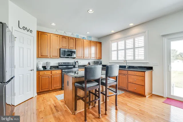 a kitchen with stainless steel appliances granite countertop wooden cabinets a stove a sink and a refrigerator