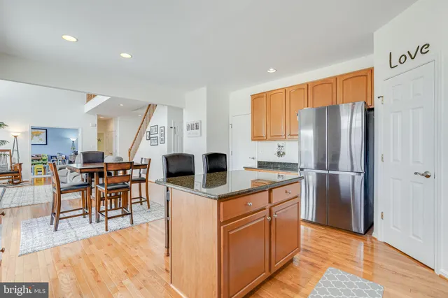 a kitchen with stainless steel appliances granite countertop a table chairs and a refrigerator