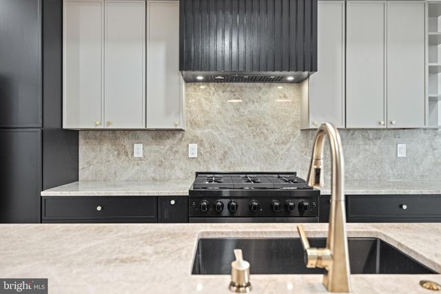 a kitchen with granite countertop a sink a stove refrigerator and cabinets