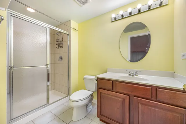 a bathroom with a toilet sink vanity granite and shower