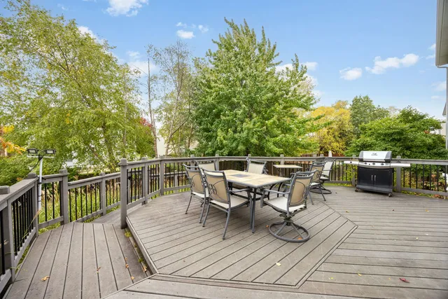 a view of a roof deck with table and chairs a barbeque with wooden floor and fence