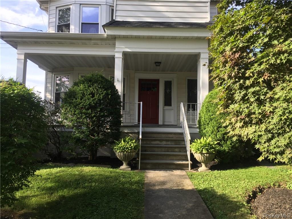 a view of a house with potted plants and a yard in front of it