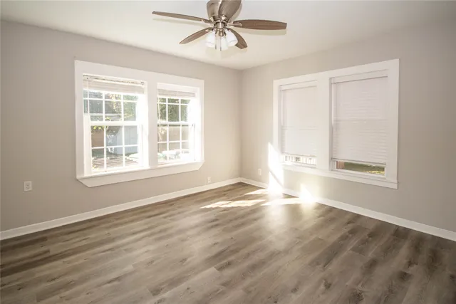 a view of an empty room with wooden floor and a window