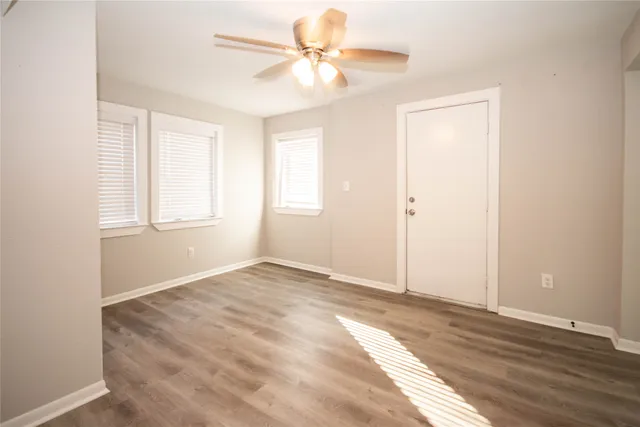 an empty room with windows and fan