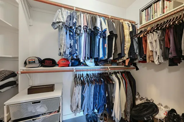 a view of walk in closet with clothes and shoes