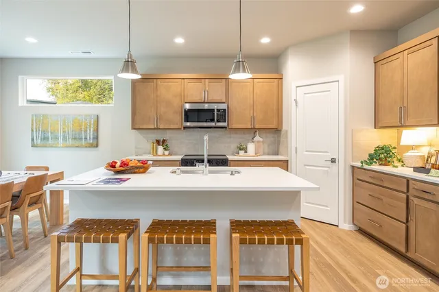 a living room with furniture and kitchen view with wooden floor