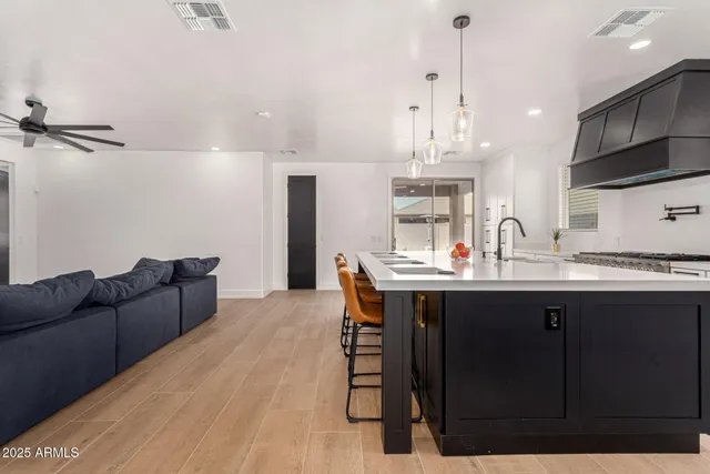 a kitchen with stainless steel appliances granite countertop a sink dishwasher a stove a refrigerator and a dining table with wooden floor