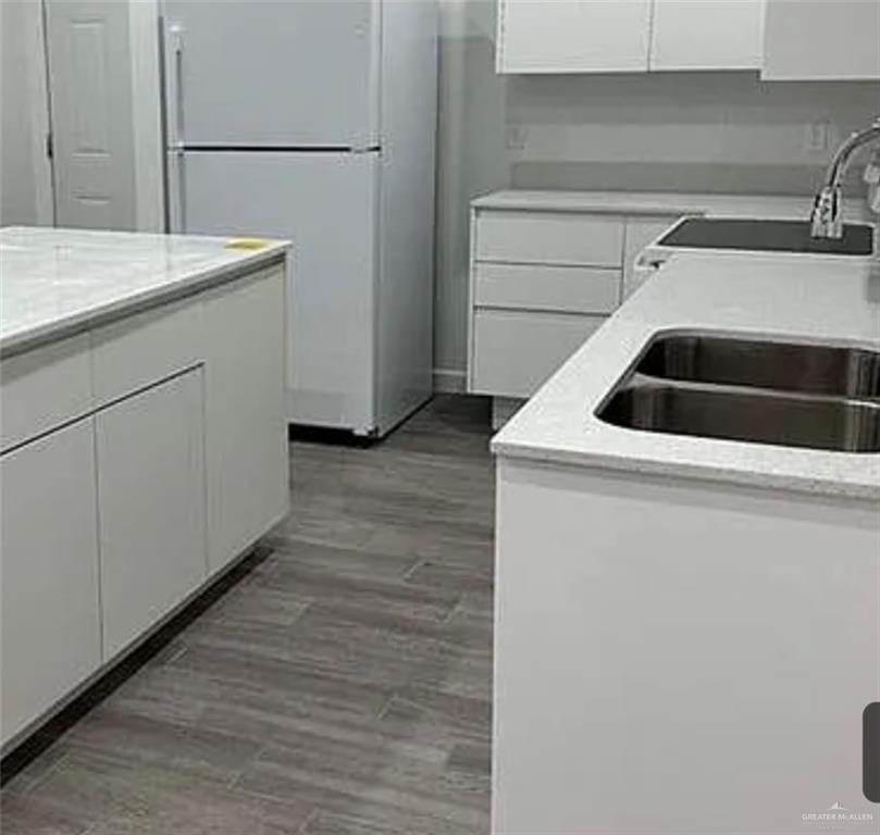 1312 Lore Drive, Unit 1 Weslaco, TX 78599 - Photo 3 of 10 Kitchen with white cabinets, freestanding refrigerator, light wood-type flooring, and light stone countertops