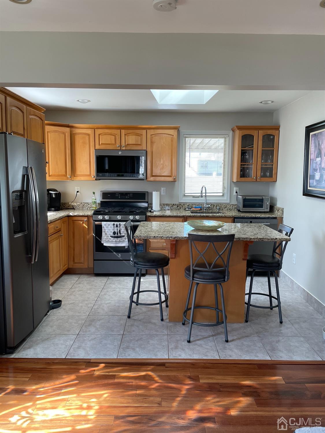 43 Brookville Road Edison, NJ 08817 - Photo 2 of 31 a kitchen with stainless steel appliances granite countertop a stove top oven a sink dishwasher a dining table and chairs with wooden floor