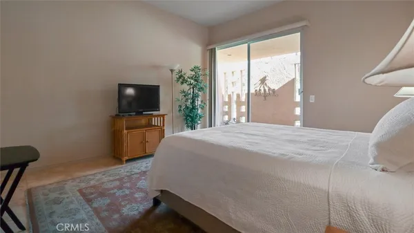 a bedroom with a bed and a flat tv screen on the dresser