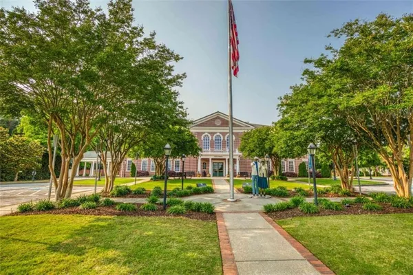 a front view of a building with a garden and trees