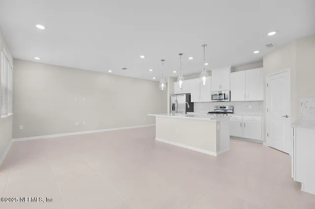 a view of kitchen with kitchen island white cabinets and stainless steel appliances