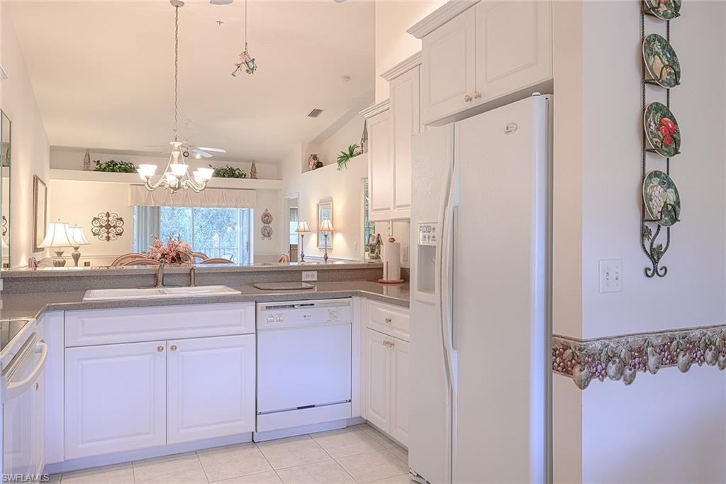 8640 Cedar Hammock Circle, Unit 523 Naples, FL 34112 - Photo 11 of 29 a kitchen with white cabinets and chandelier