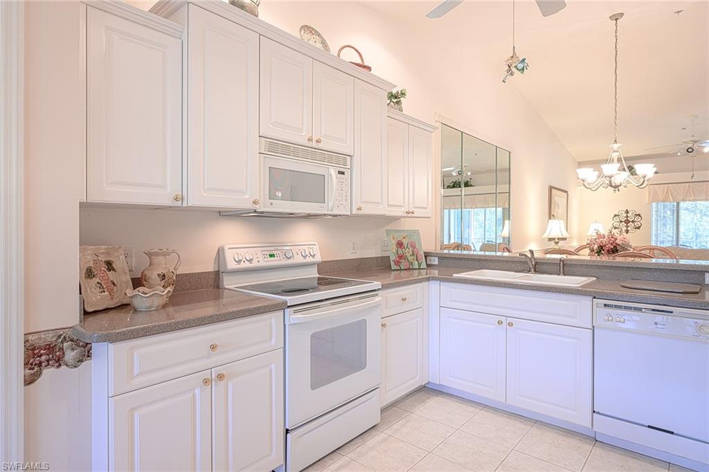 8640 Cedar Hammock Circle, Unit 523 Naples, FL 34112 - Photo 9 of 29 a kitchen with white cabinets and white appliances