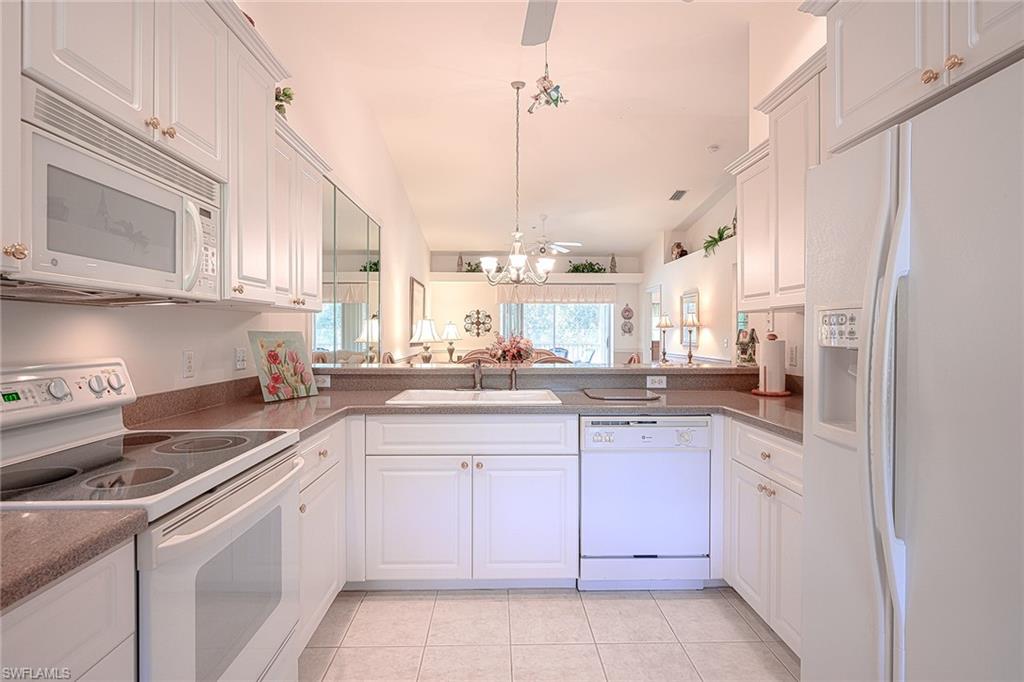8640 Cedar Hammock Circle, Unit 523 Naples, FL 34112 - Photo 10 of 29 a kitchen with white cabinets and white appliances