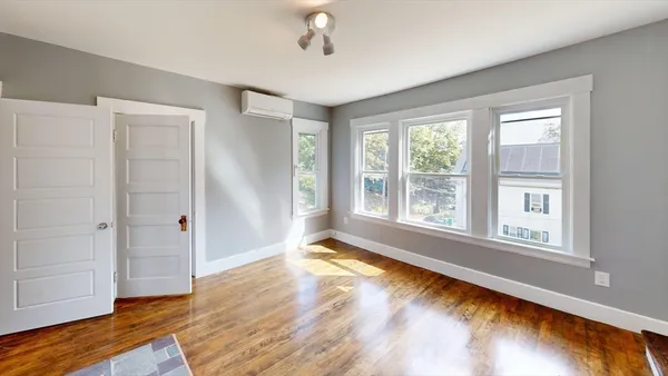a view of an empty room with wooden floor and a window