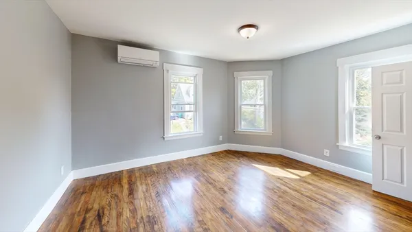 a view of empty room with wooden floor and fan