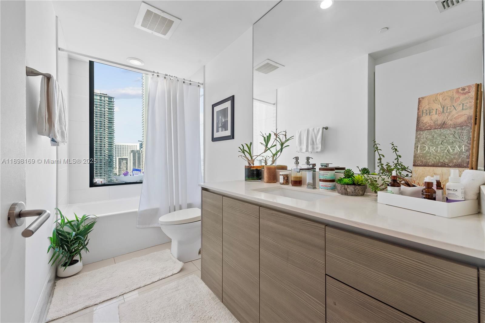 460 Northeast 28th Street, Unit 1901 Miami, FL 33137 - Photo 12 of 34 a bathroom with a double vanity sink toilet and a mirror
