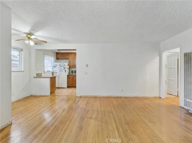 a view of empty room with wooden floor and kitchen view