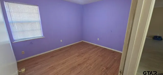 a view of empty room with wooden floor and entryway