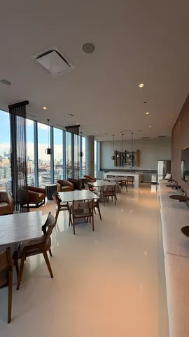 a room with lots of tables a large window and chairs