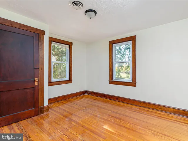 a view of an empty room with window and wooden floor