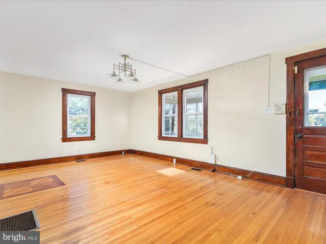 a view of an empty room with window and wooden floor