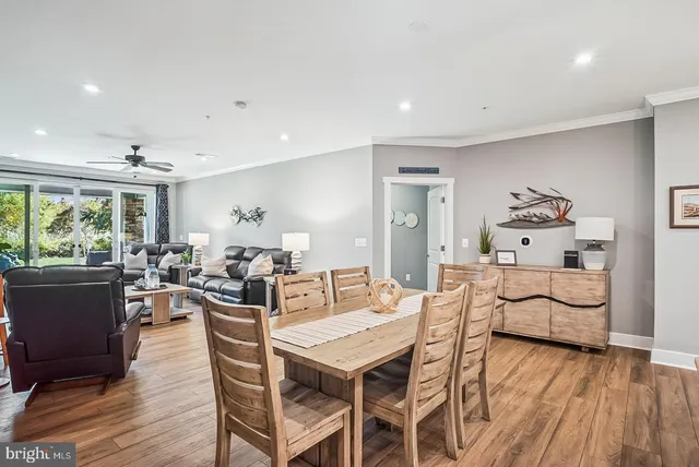 a living room with furniture kitchen view and a wooden floor