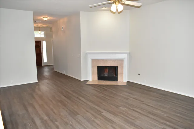 a view of an empty room with wooden floor and a fireplace