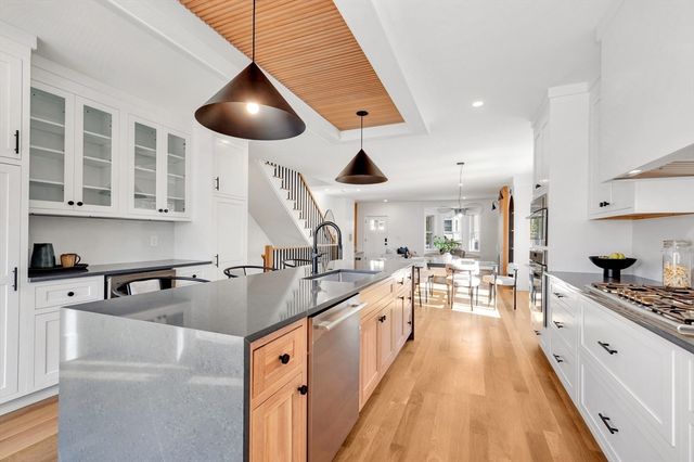a kitchen with stainless steel appliances granite countertop a sink a stove and a wooden floors
