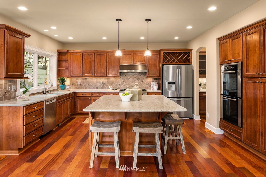 110 N 50th Street Seattle, WA 98103 - Photo 8 of 25 a kitchen with stainless steel appliances kitchen island granite countertop a table chairs and a refrigerator
