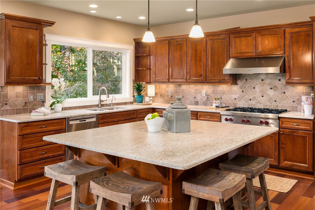 110 N 50th Street Seattle, WA 98103 - Photo 9 of 25 a kitchen with a stove a sink a kitchen island with chairs and wooden cabinets