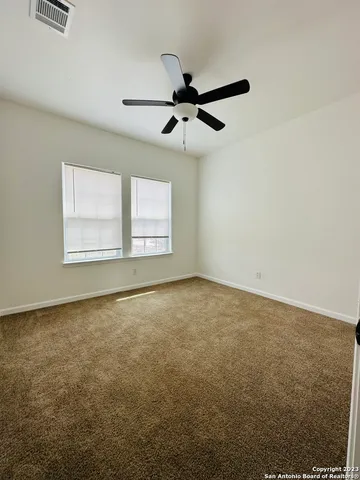 an empty room with a window and a ceiling fan
