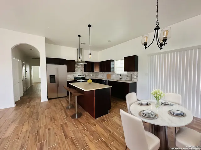 a kitchen with stainless steel appliances granite countertop a sink dishwasher a stove a dining table and chairs with wooden floor