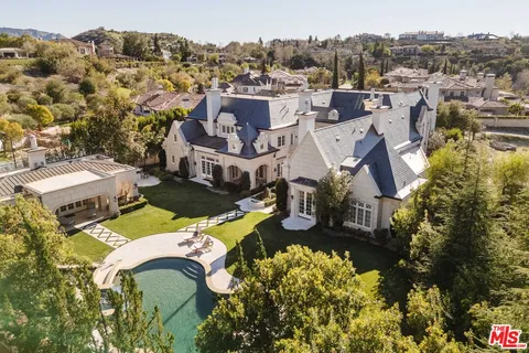 an aerial view of a house with a swimming pool a yard and mountain view in back