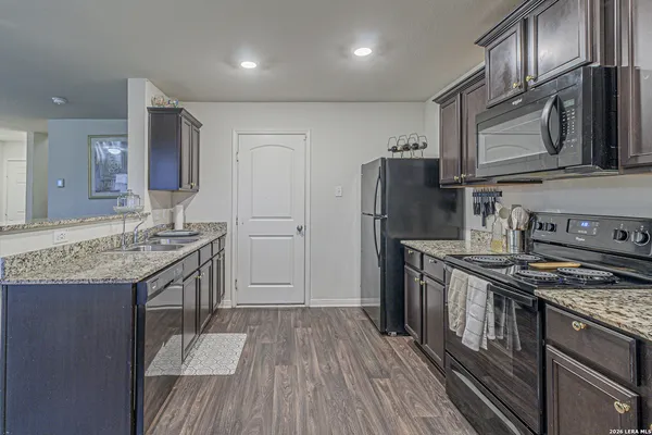 a kitchen with granite countertop a sink stove and refrigerator