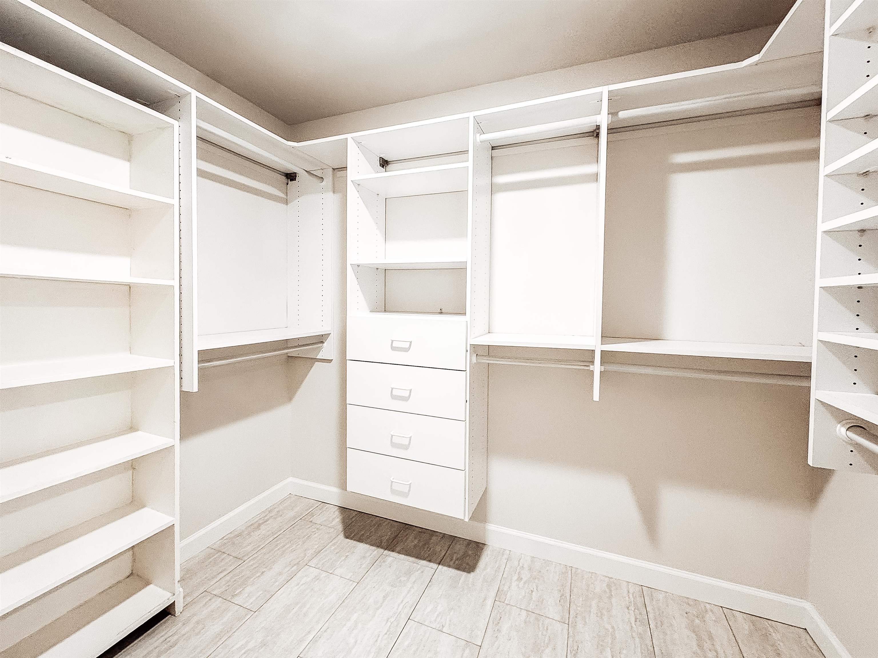 832 South Tree Drive Collierville, TN 38017 - Photo 31 of 40 Custom walk-in closet featuring extensive built-in shelving, multiple hanging rods, four integrated drawers with chrome hardware, and wood-finish flooring