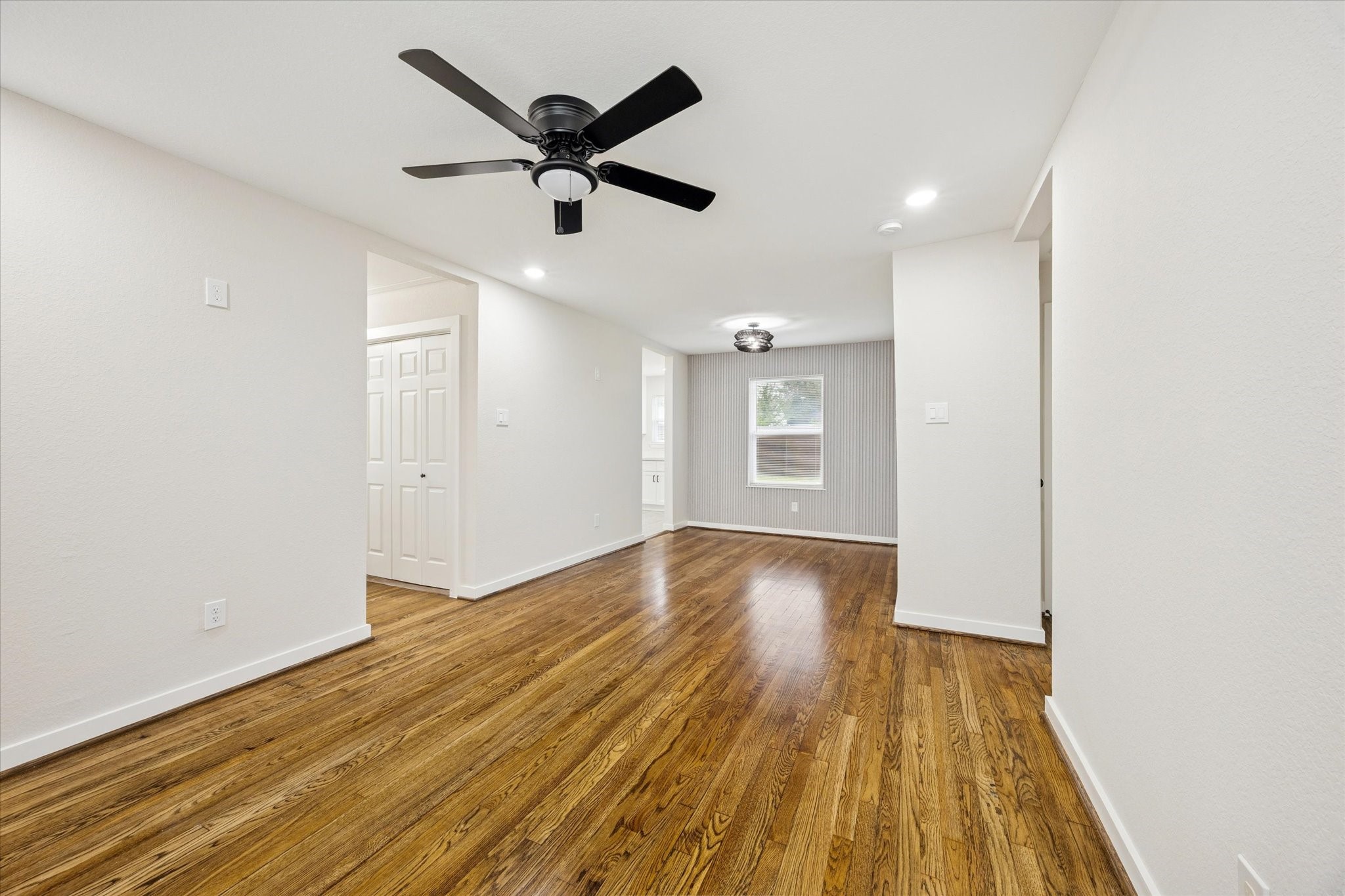 a view of empty room with wooden floor and fan