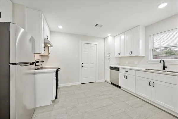 a kitchen with a sink a refrigerator and cabinets