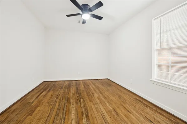 an empty room with wooden floor cabinet and windows